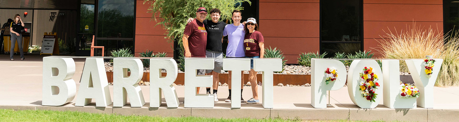Barrett student and family in front of ASU Polytechnic campus and large Barrett Poly sign