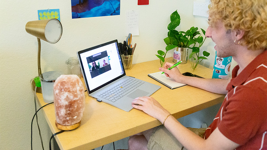 Student on Zoom call on laptop inside dorm room