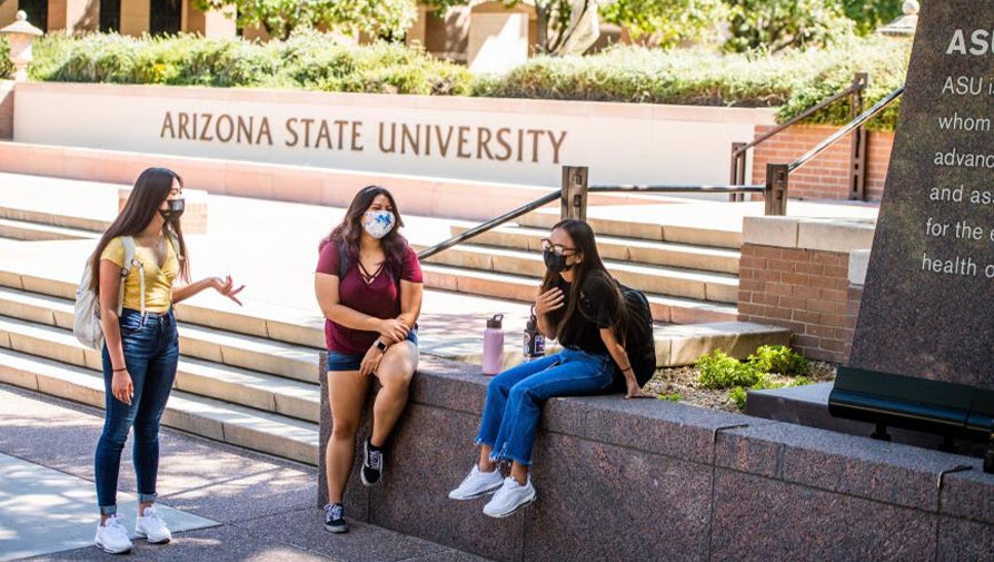 Three students talking in front of the ASU Charter