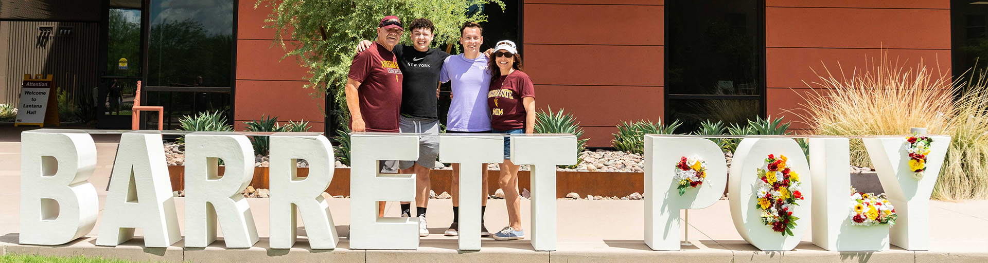 Barrett family and student next to the sign at the Polytechnic campus