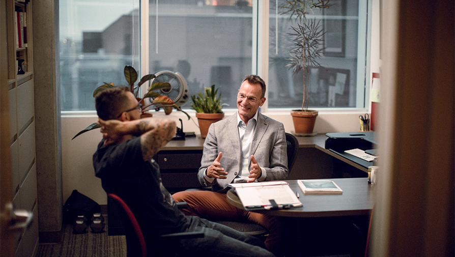 Two people in professional attire having a conversation in an office